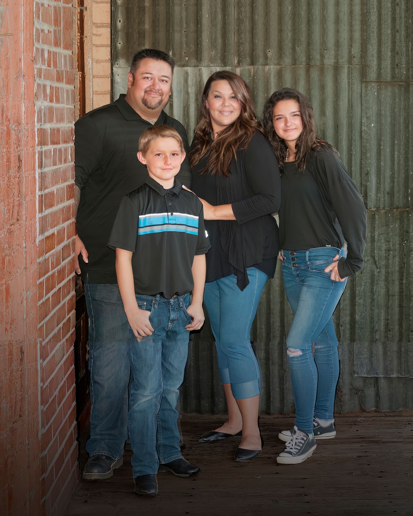 A family is posing for a picture in front of a brick wall.