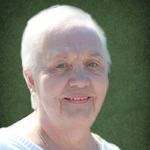 An elderly woman with white hair is smiling for the camera.