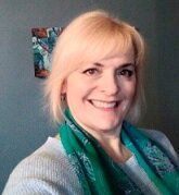 A woman wearing a green scarf is smiling for the camera.