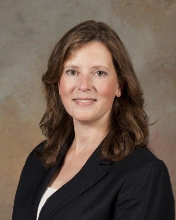 A woman in a black jacket and white shirt is smiling for the camera.