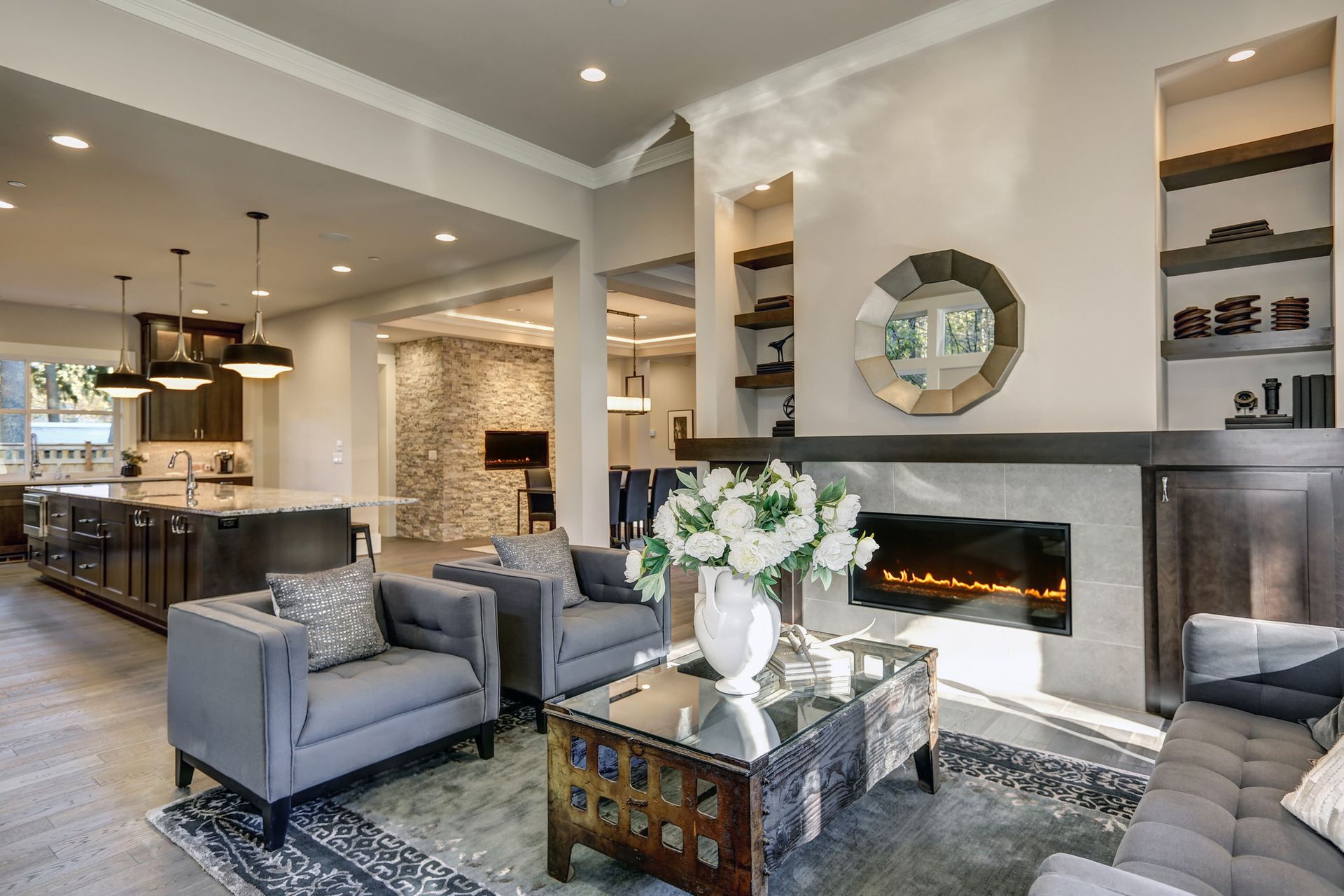 Living room with grey furniture, fireplace, and open kitchen.
