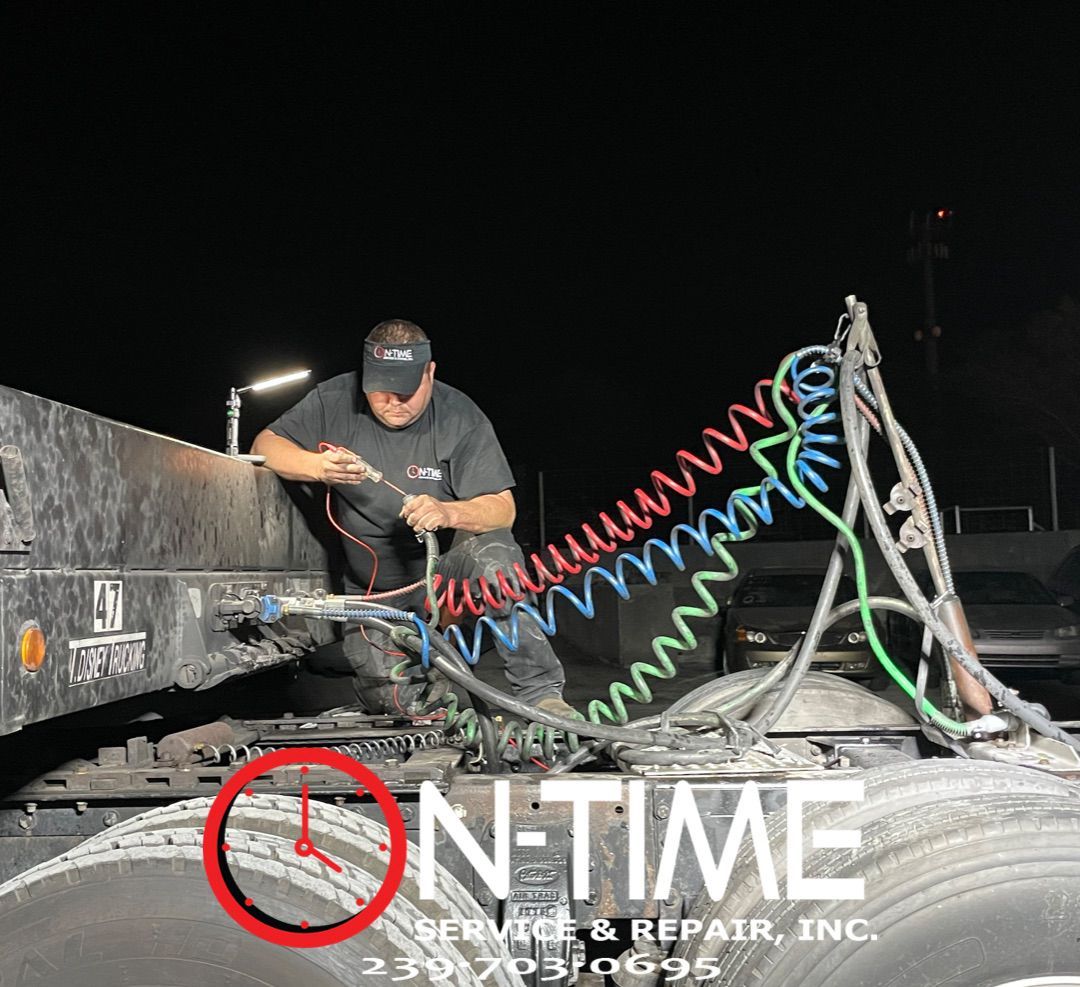 A man is working on the back of a semi truck at night.