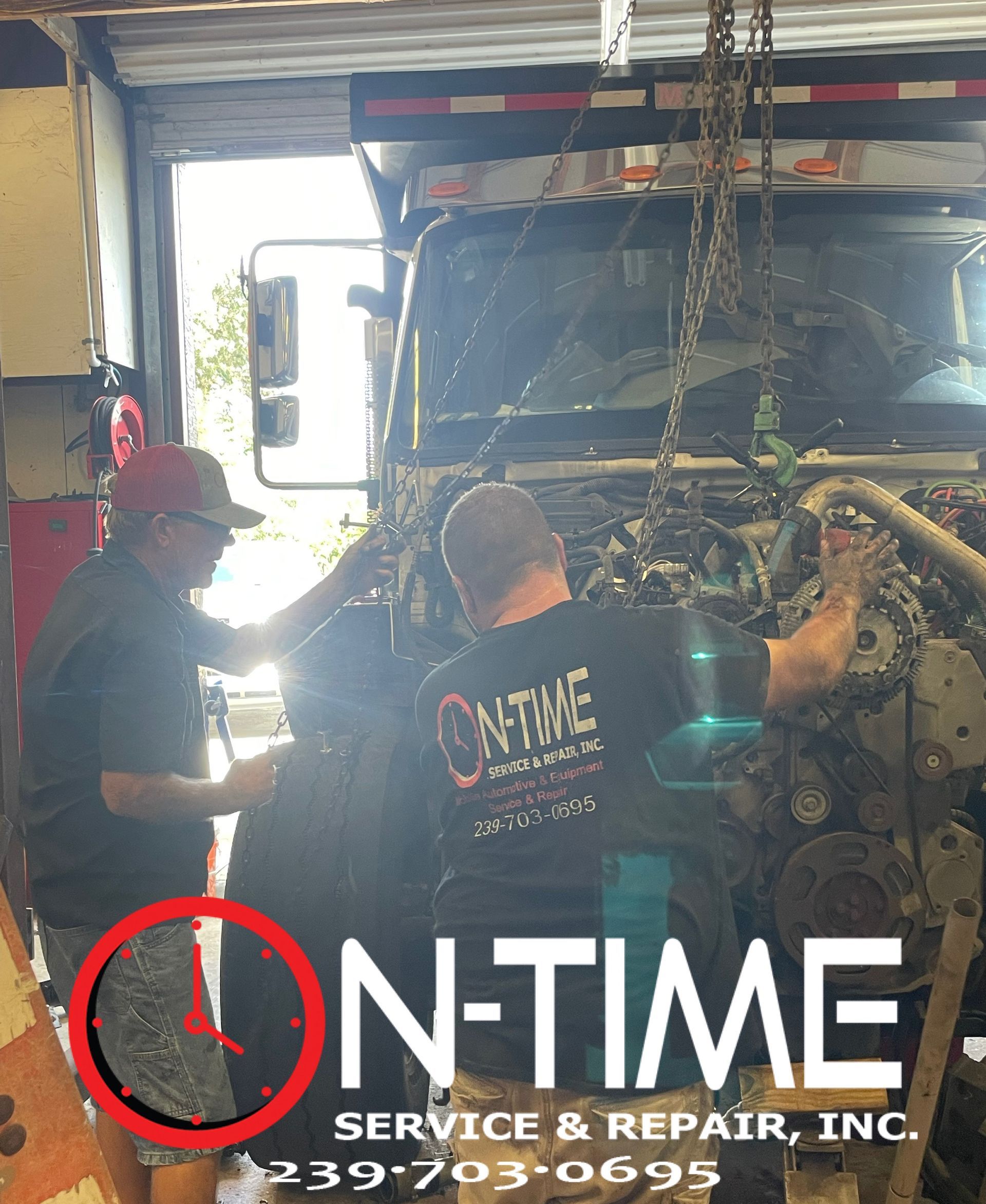 Two men are working on a truck engine in a garage.