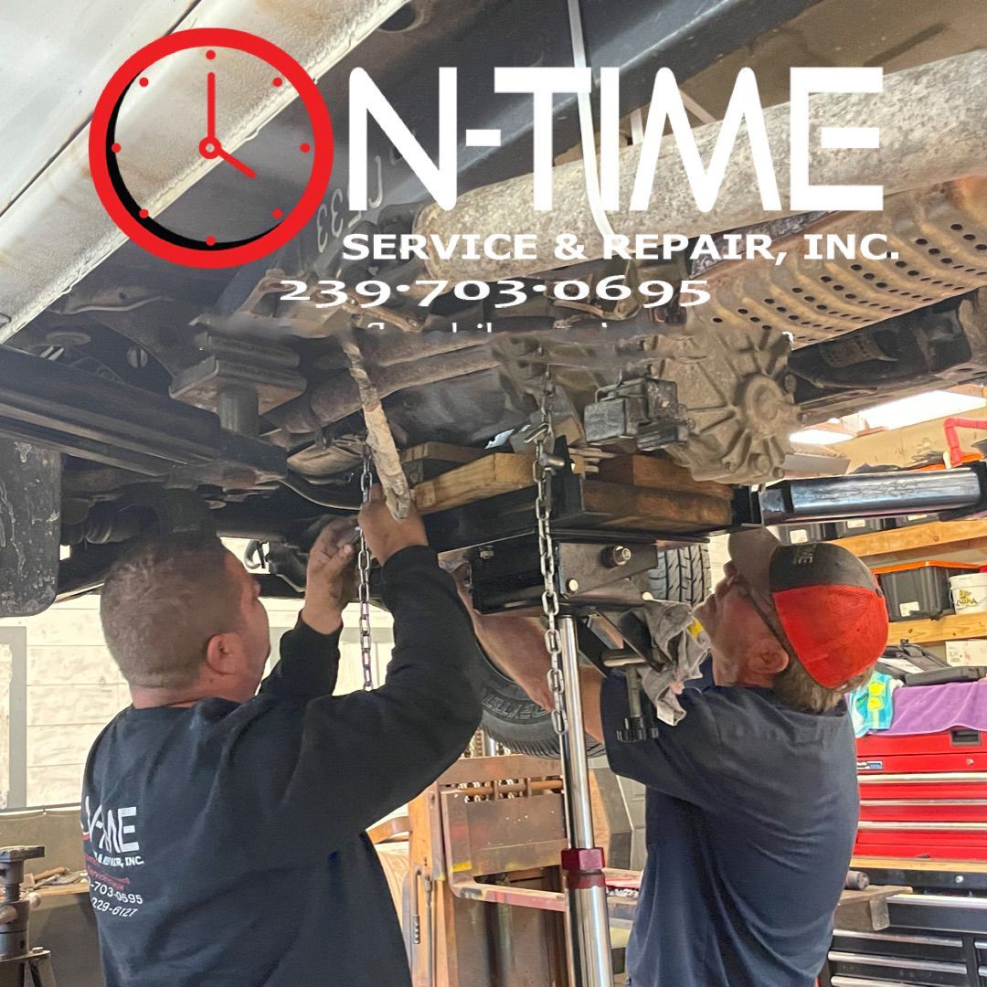 Two men are working under a car in a garage for on time service & repair inc.