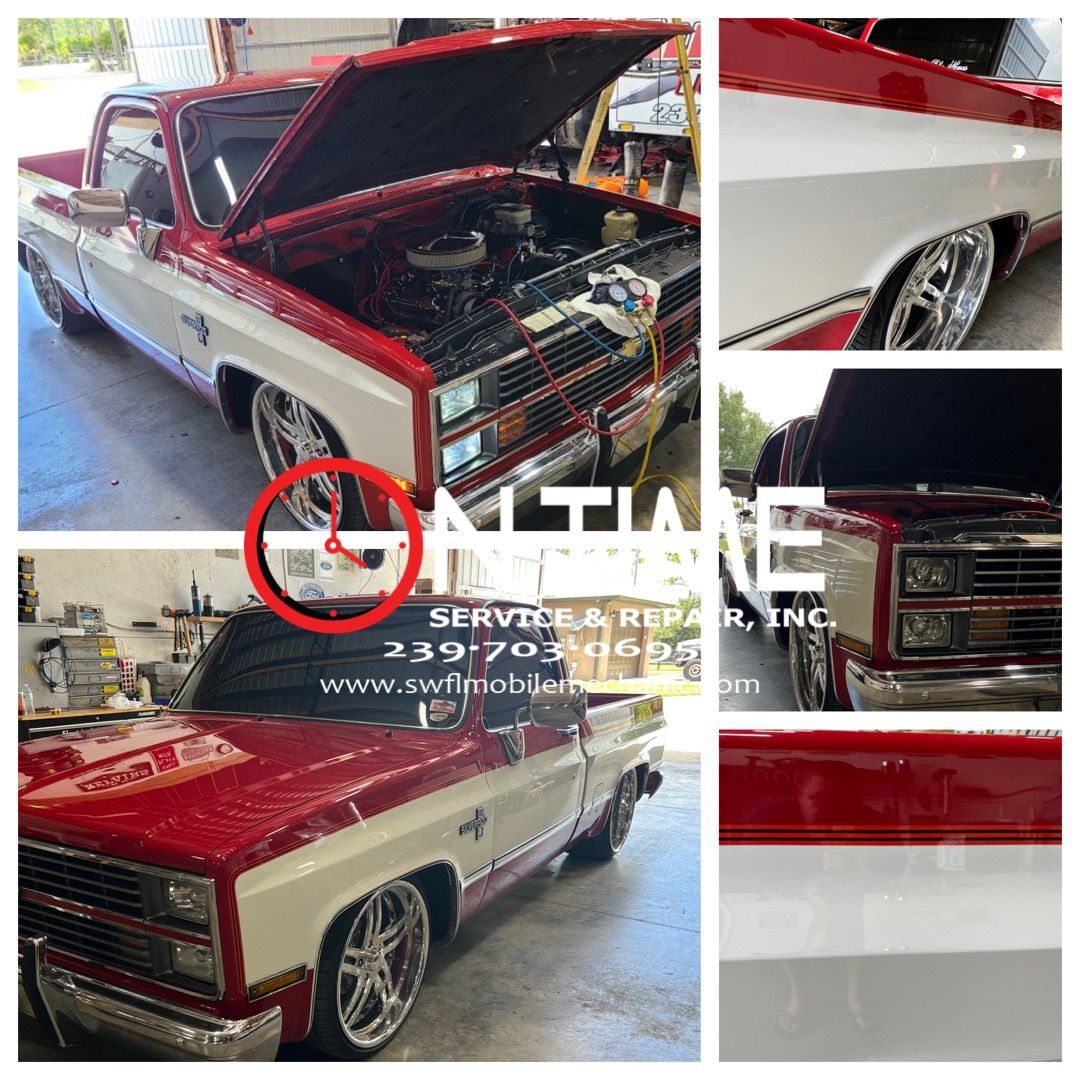 A red and white truck with the hood open is sitting in a garage.