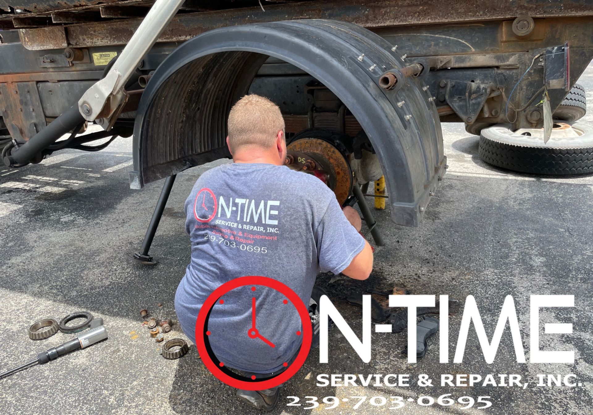 A man is kneeling on the ground working on a truck.