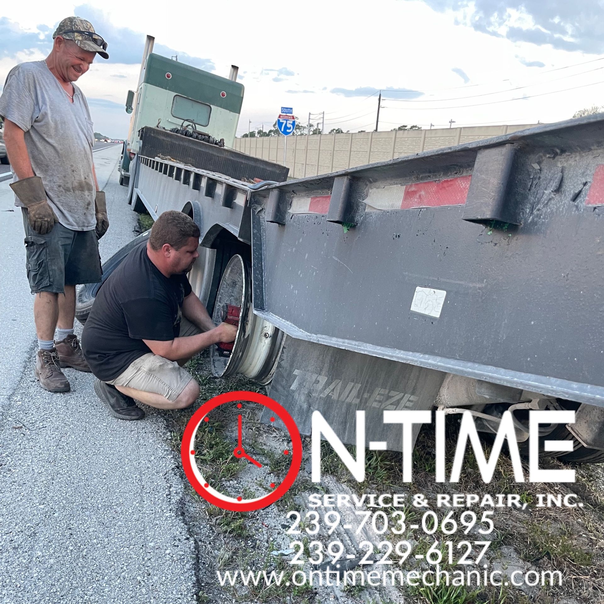 Two men are working on a trailer on the side of the road.