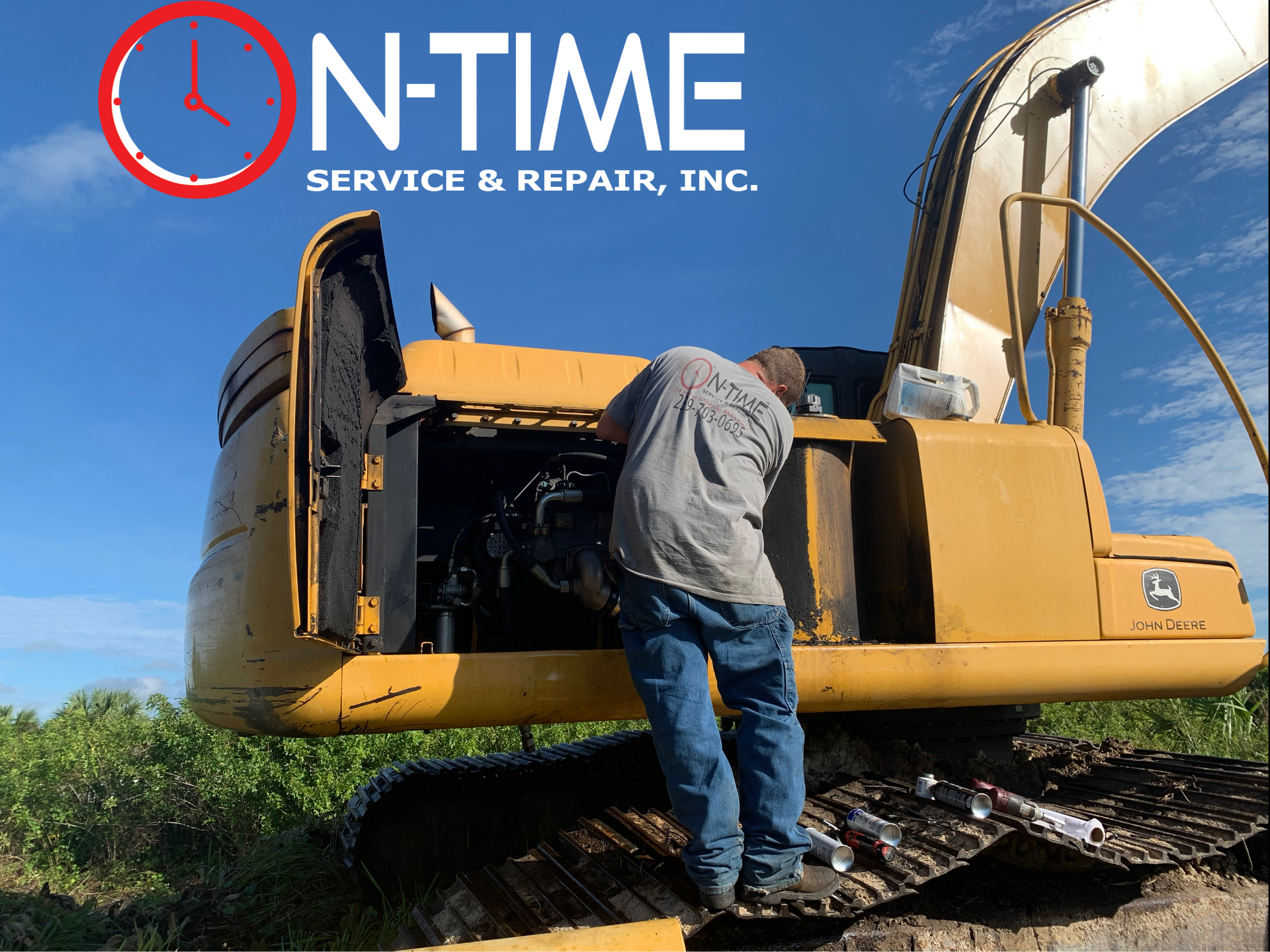 A man is working on a john deere excavator in a field.
