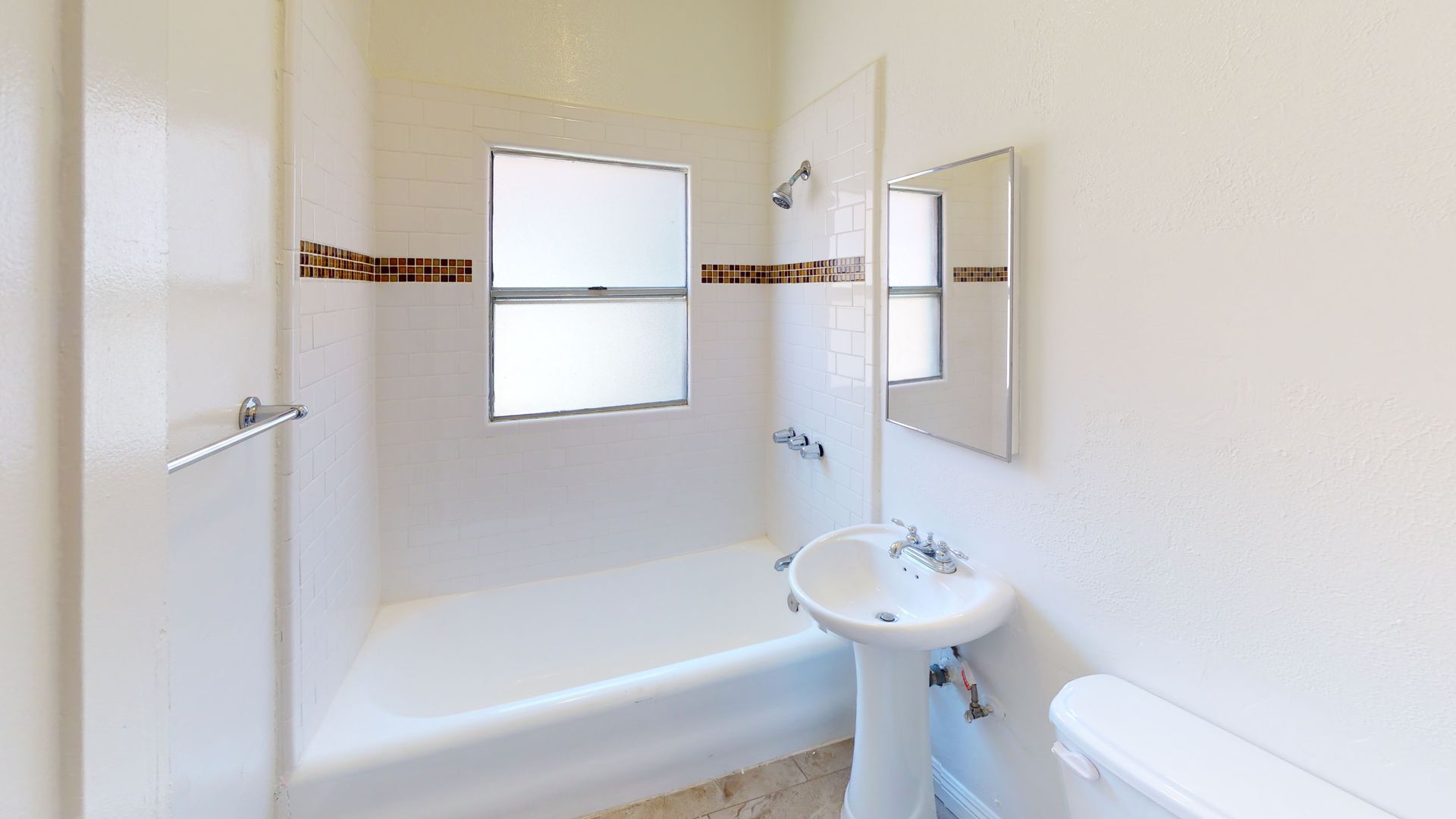 Bathroom with white fixtures, a window, a mirror, and decorative tile.