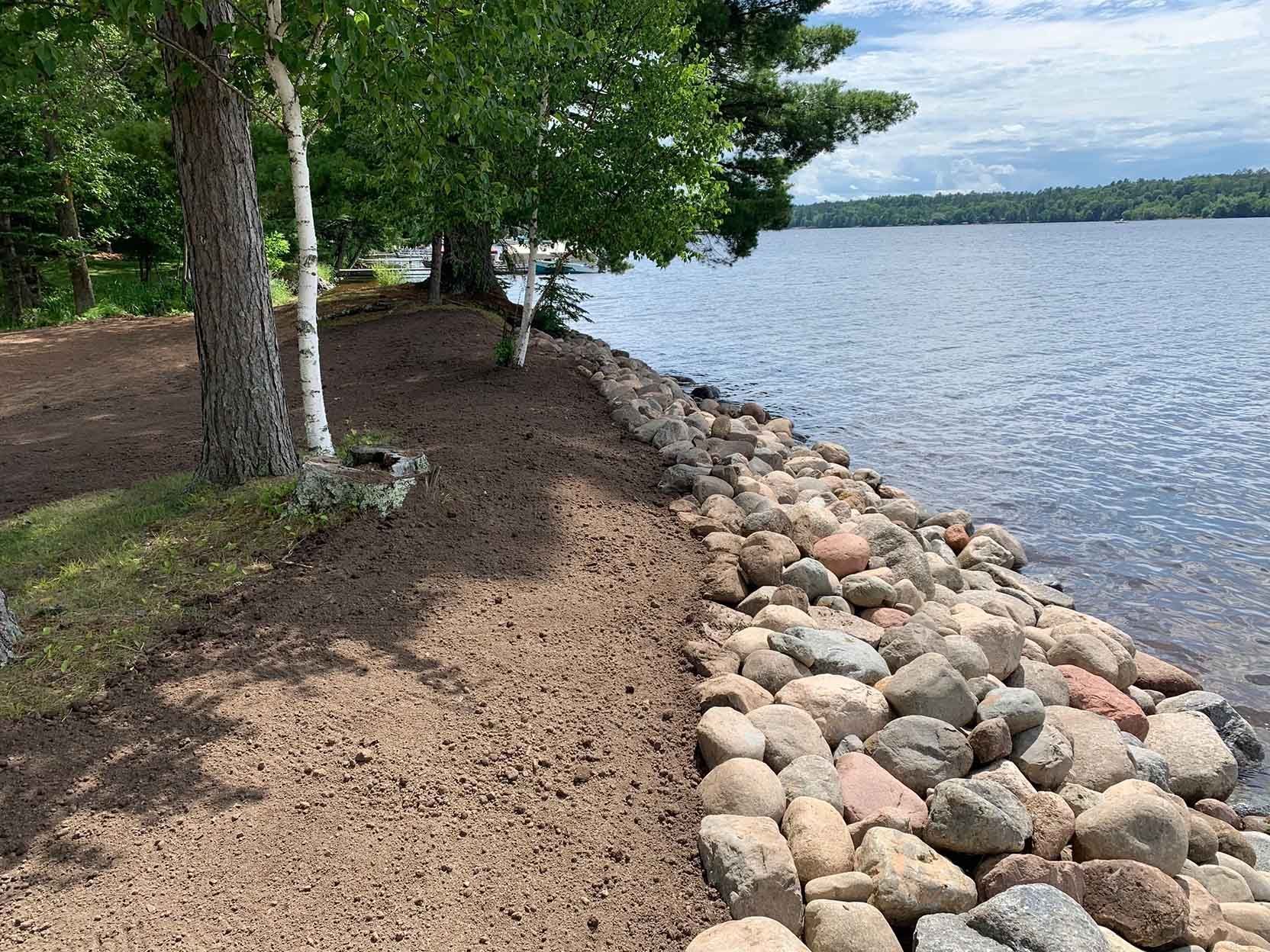 Lakeshore with trees and large rocks along the water's edge