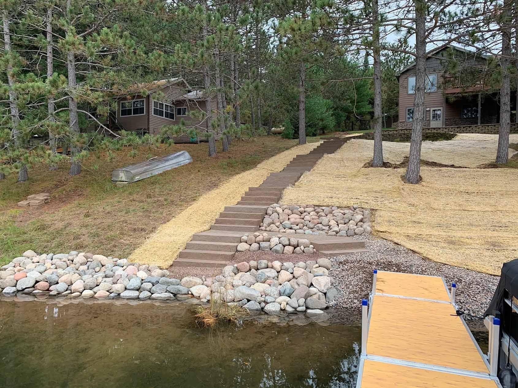 Staircase and path leading uphill from a lake dock to two cabins