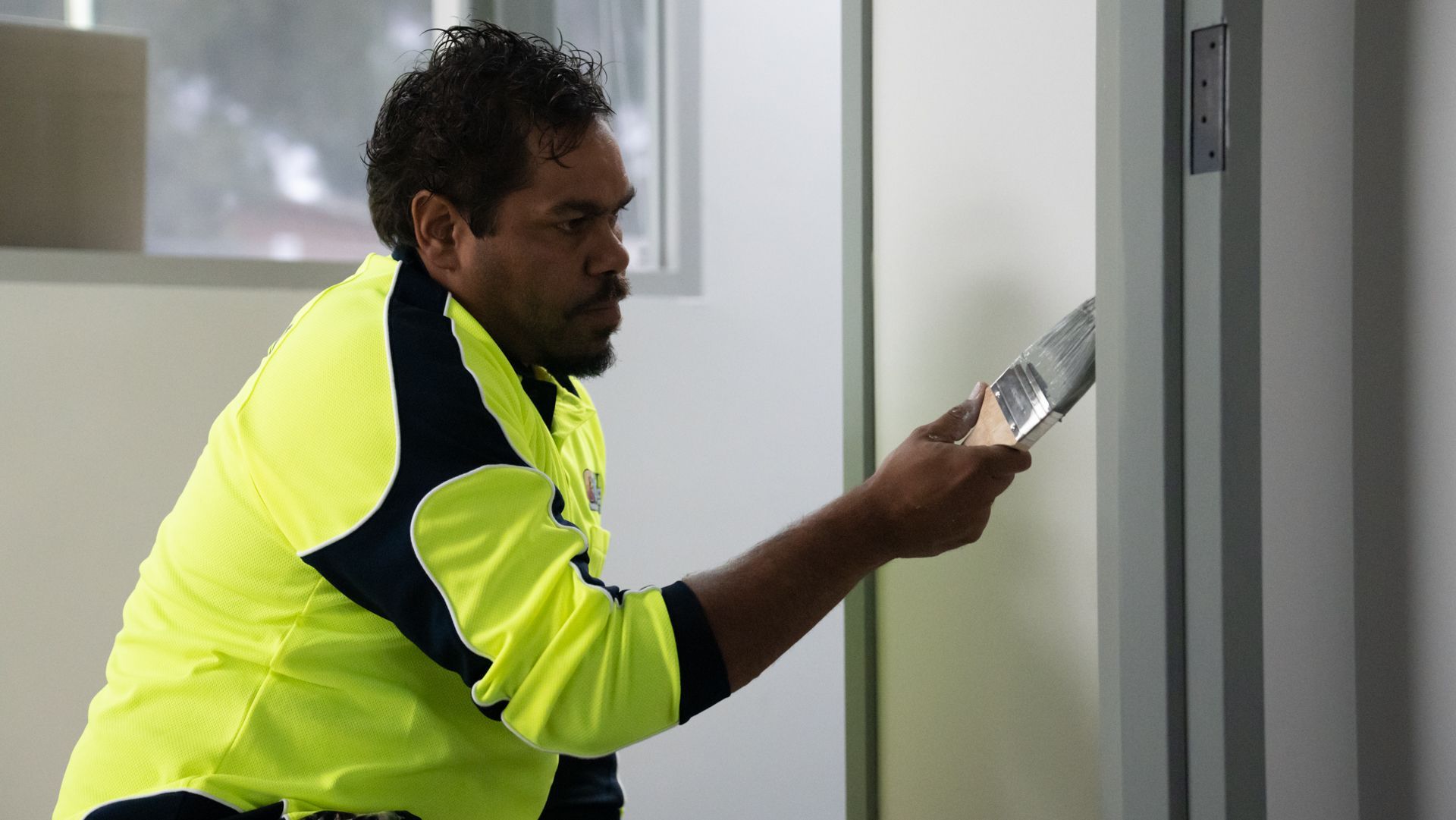 A man is painting a door with a spatula.