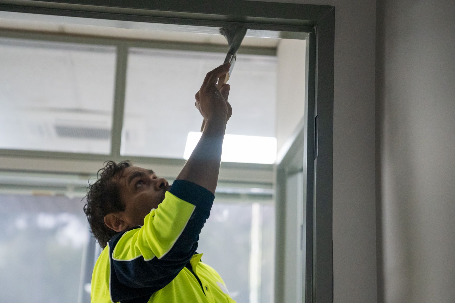 A man is painting a door frame with a brush.