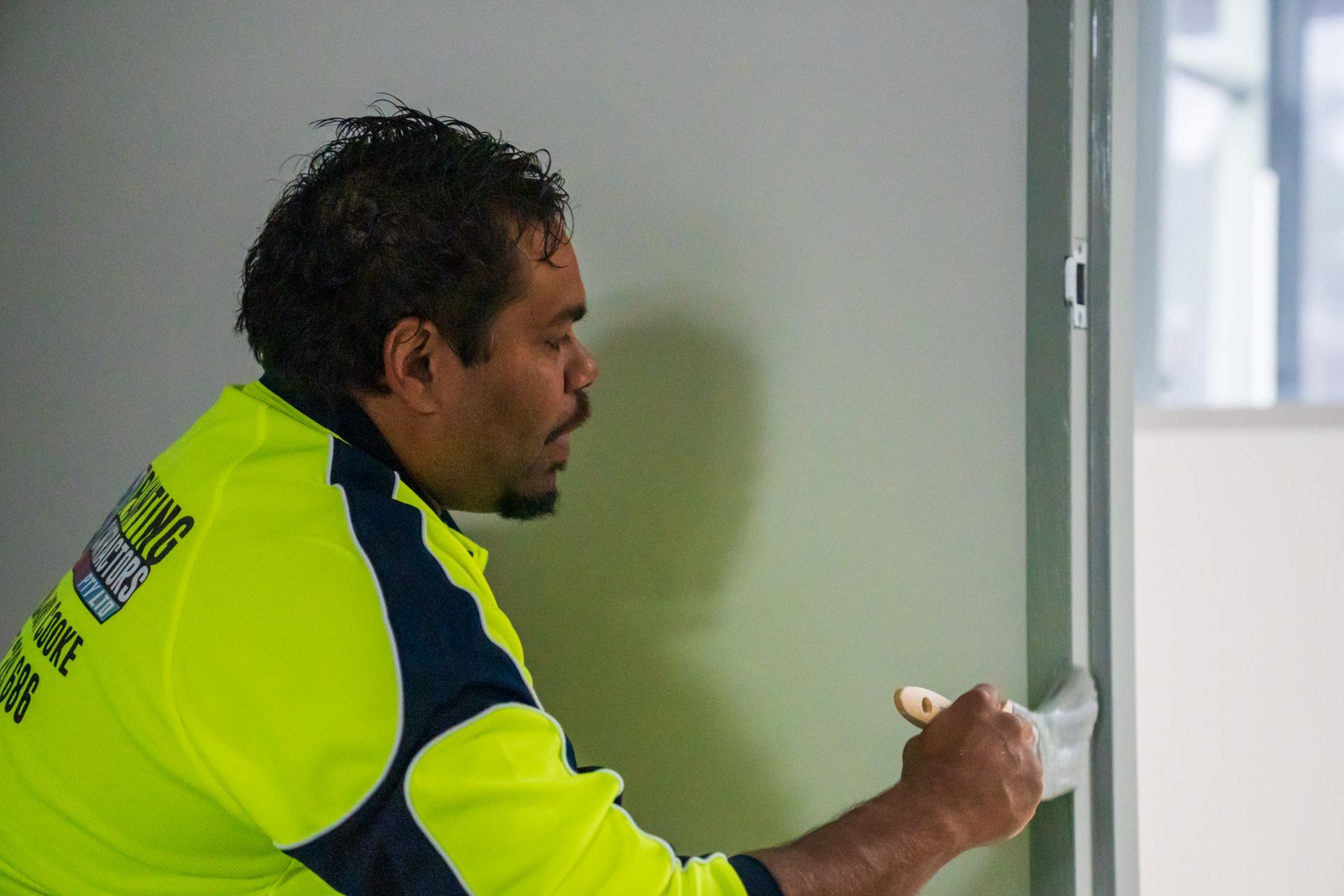A man is painting a wall with a brush.