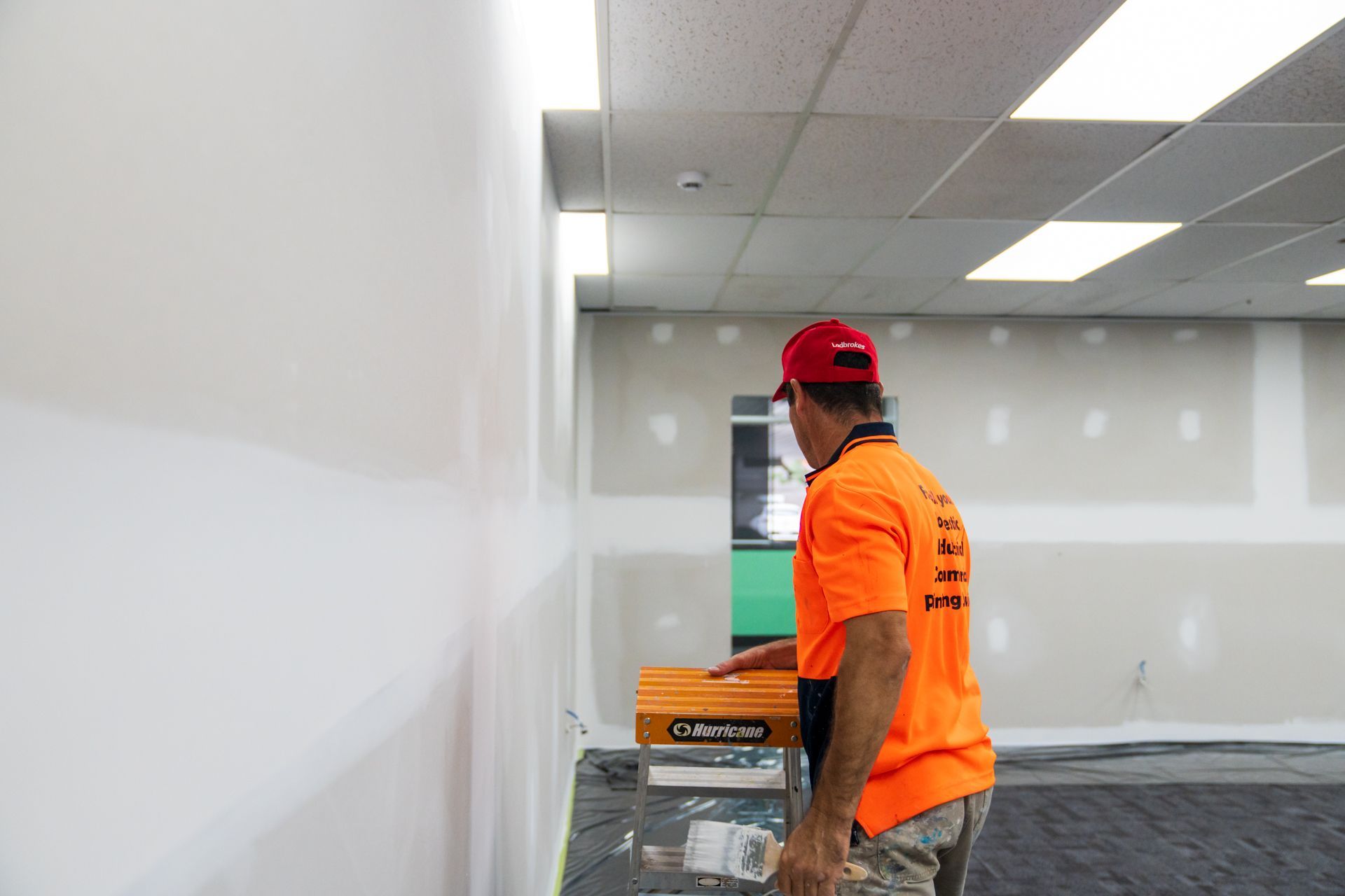 A man in an orange shirt is standing in an empty room.