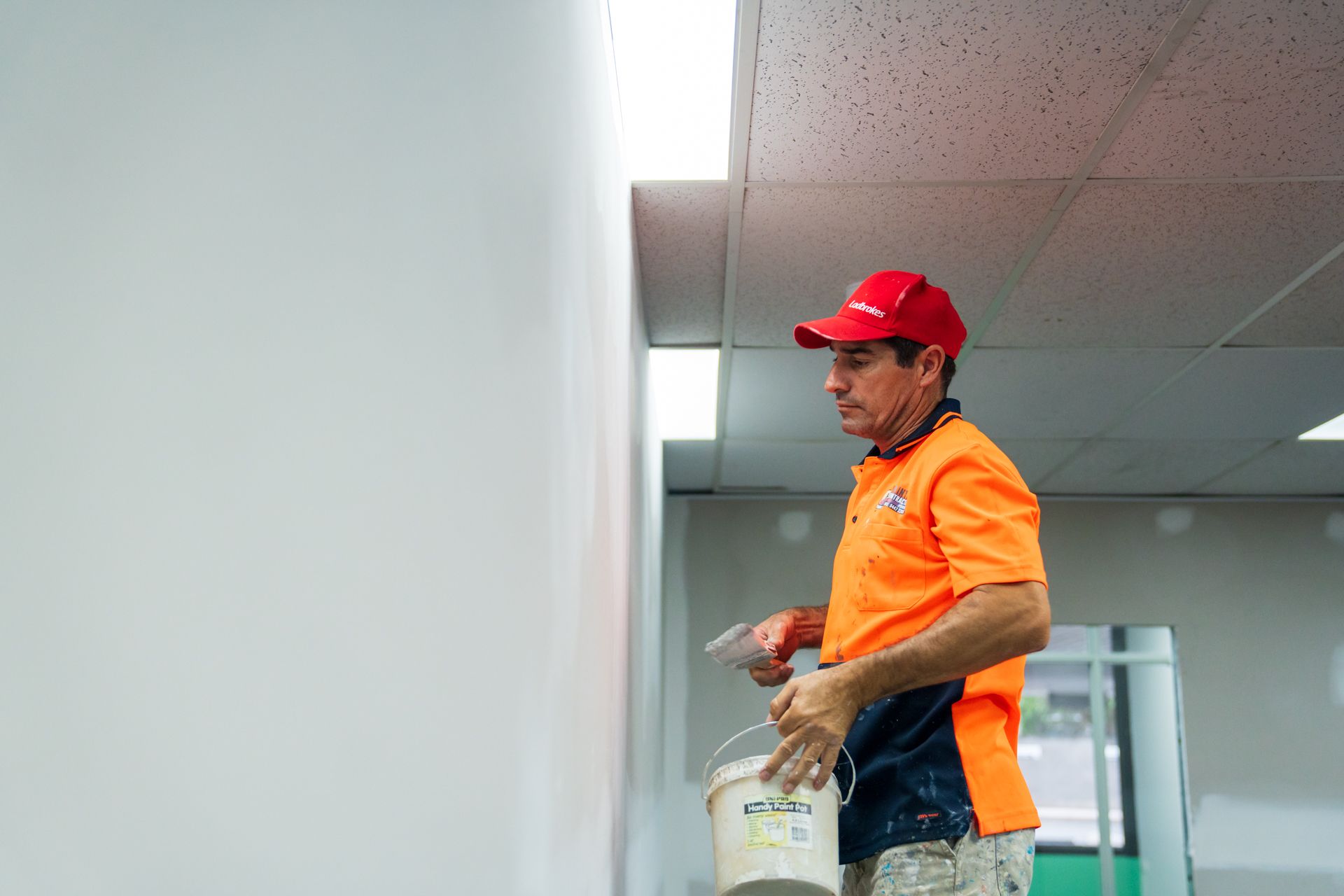 A man is painting a wall with a bucket of paint.