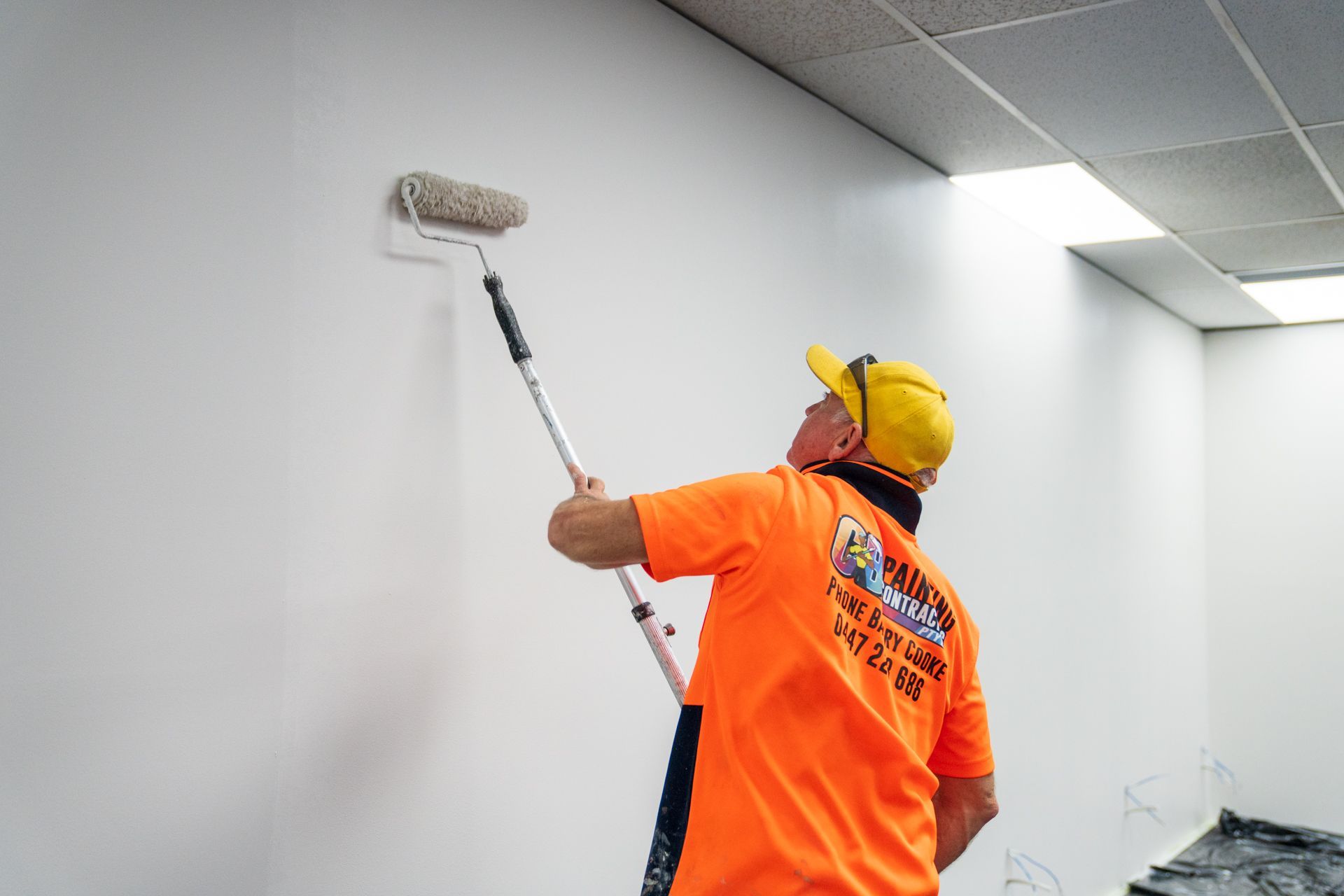 A man is painting a wall with a roller.