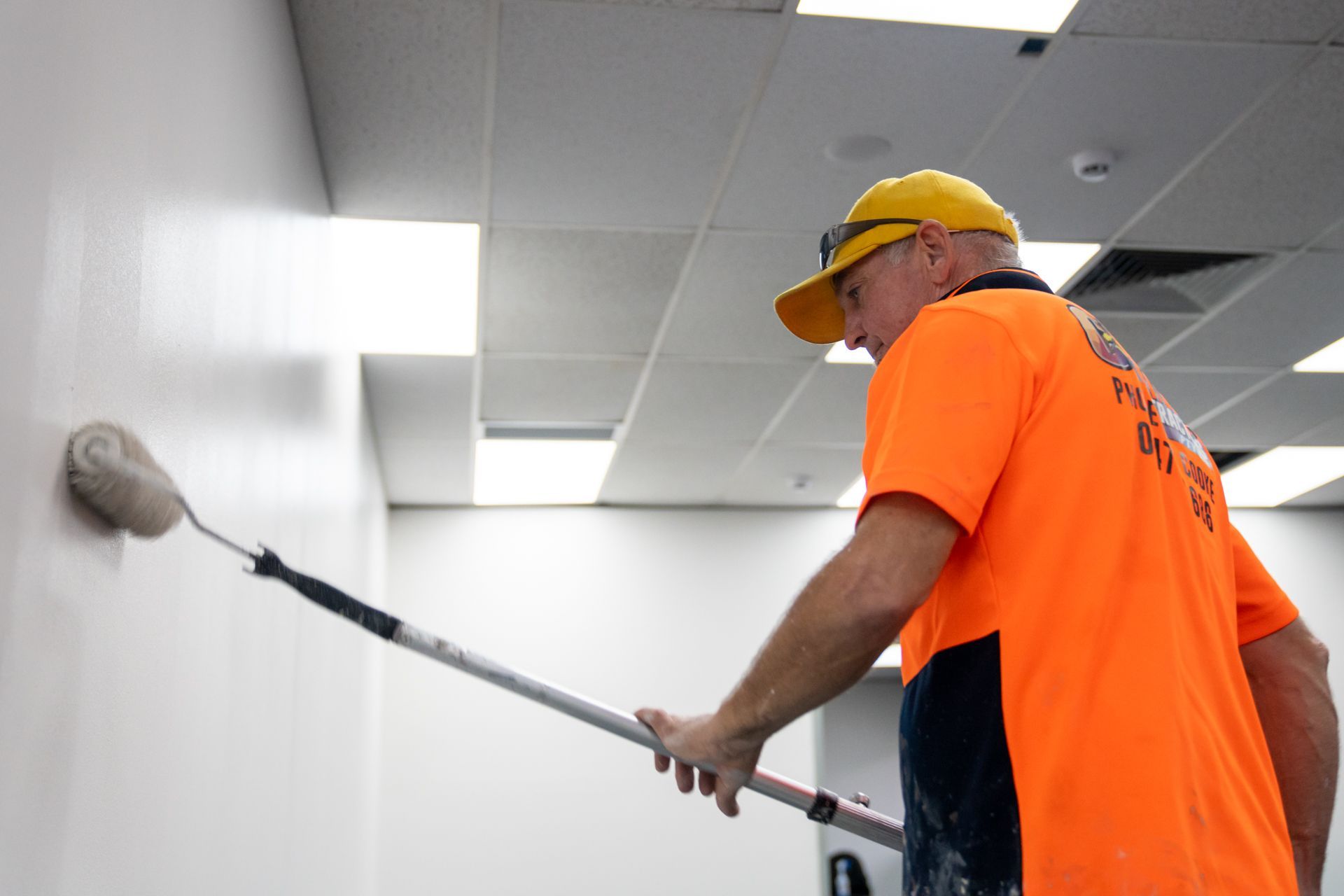 A man is painting a wall with a roller.