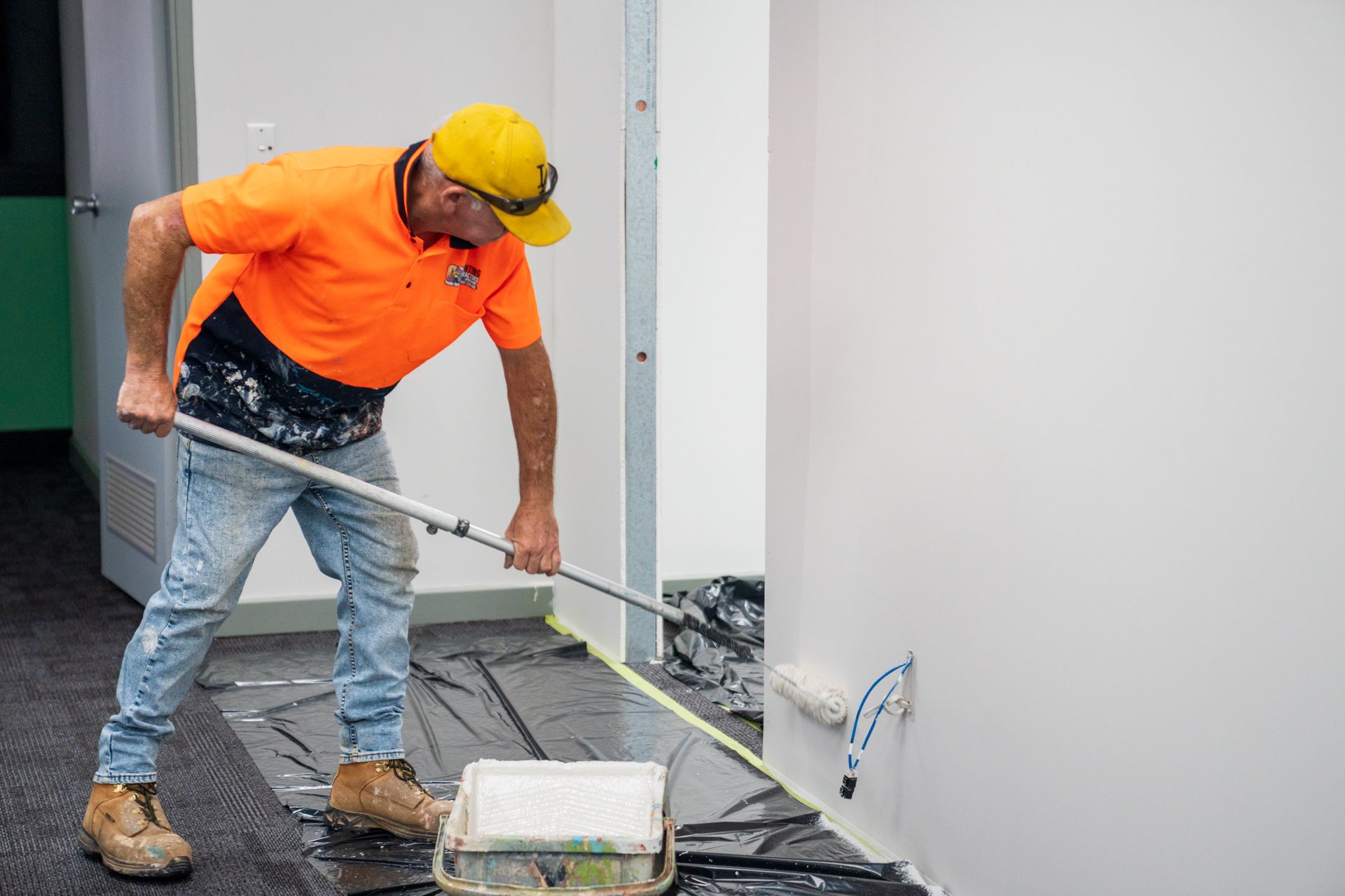 A man is painting a wall with a paint roller.