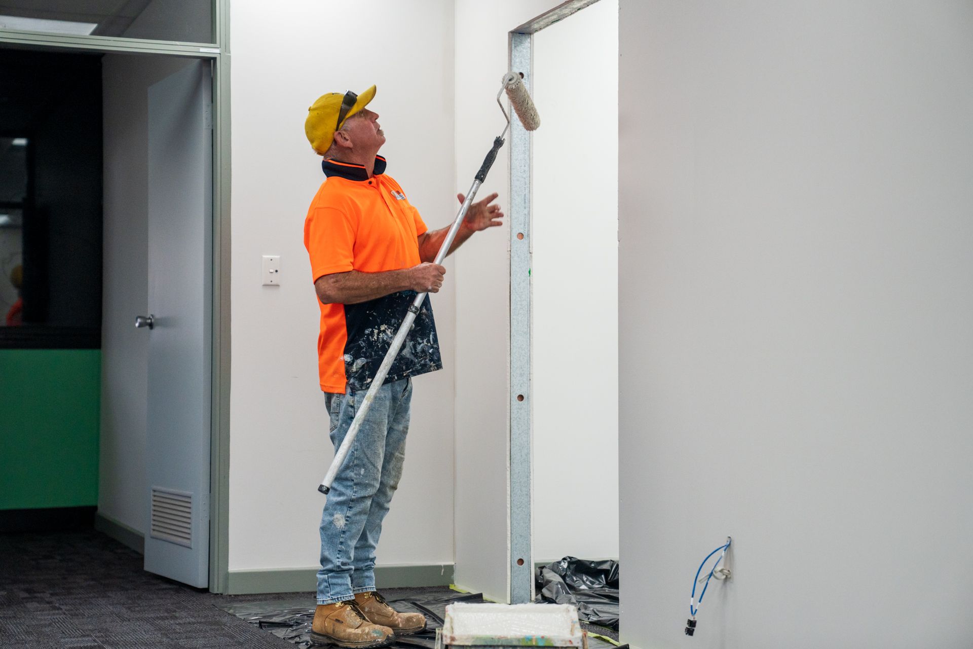 A man is painting a wall with a roller.
