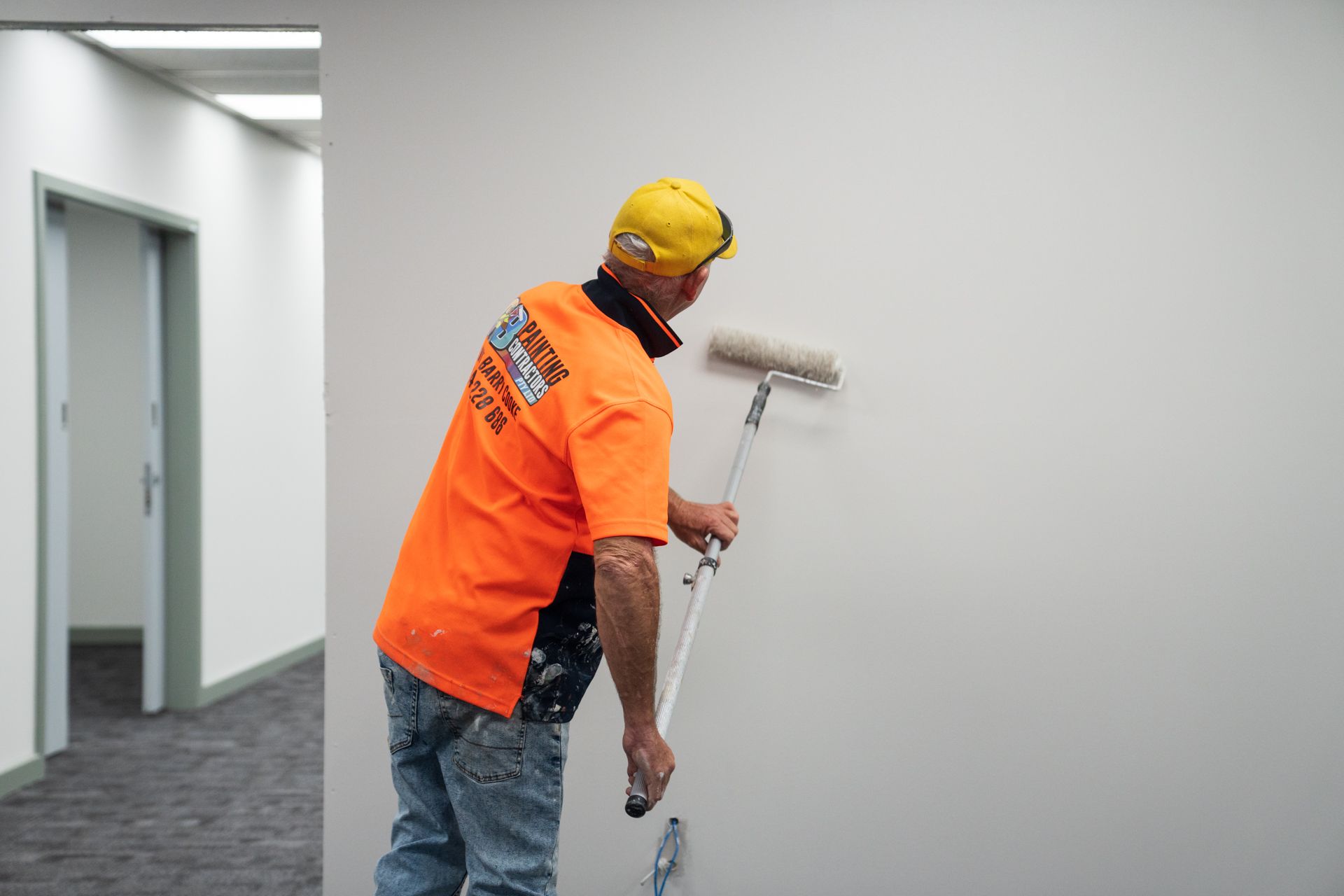 A man is painting a wall with a roller.