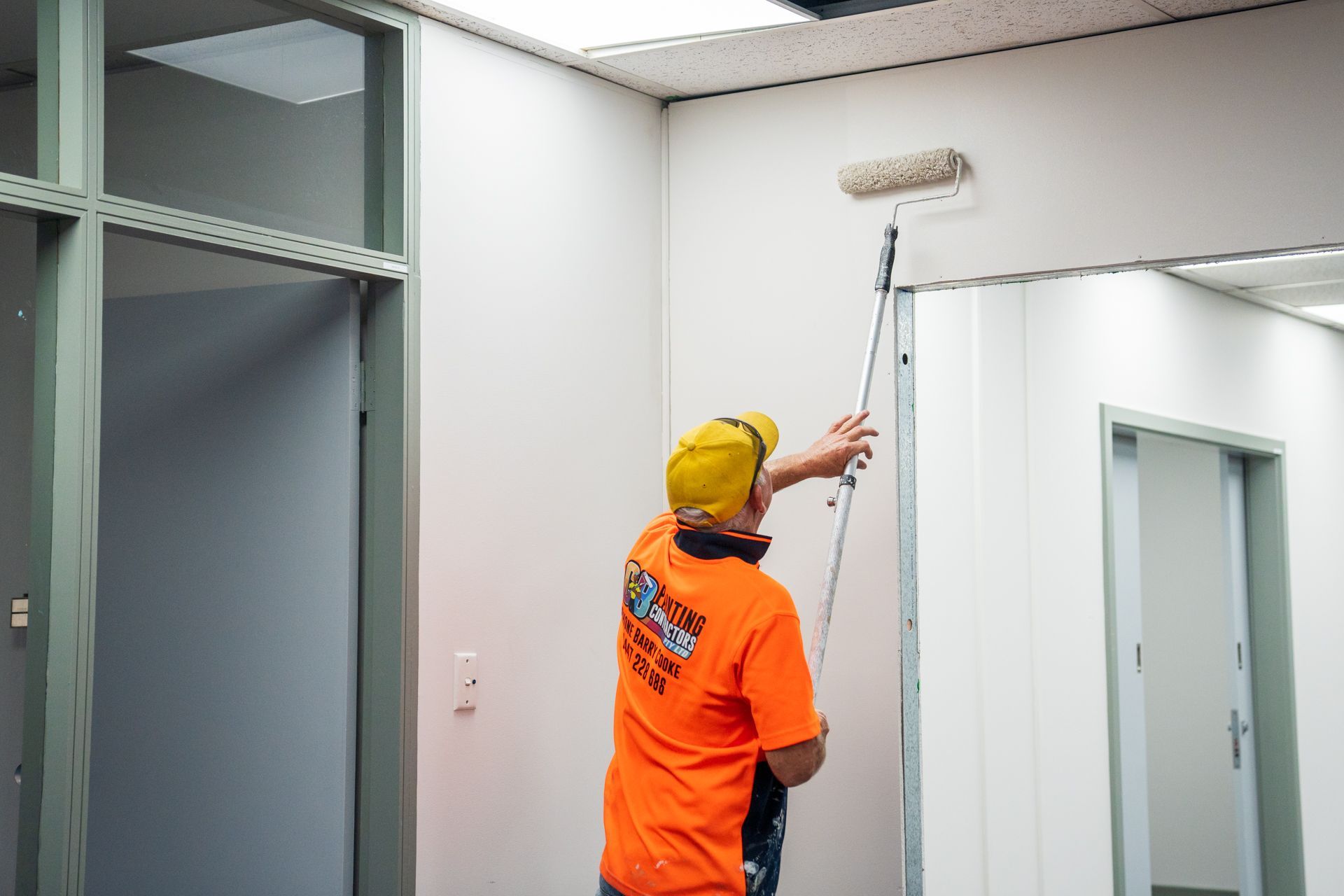 A man is painting a wall with a roller.