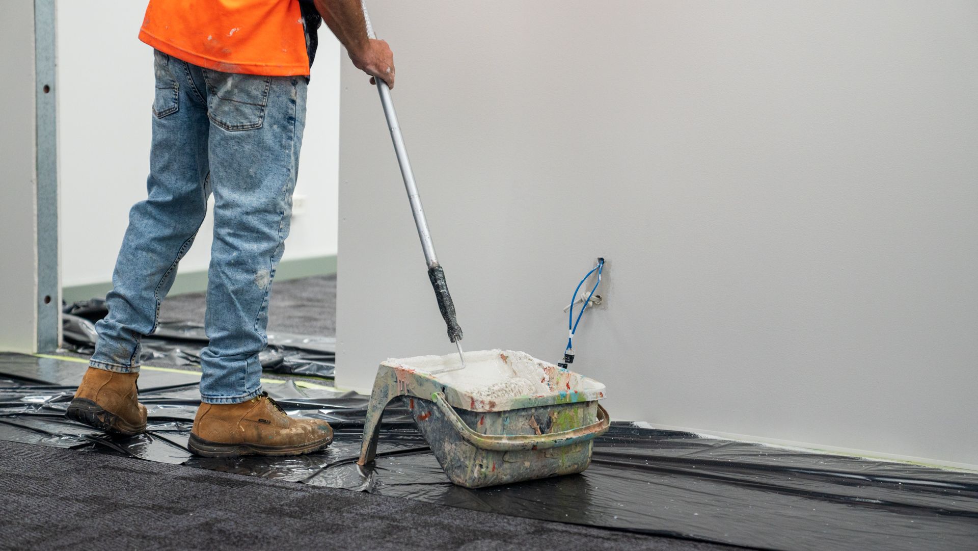 A man is painting a wall with a roller.