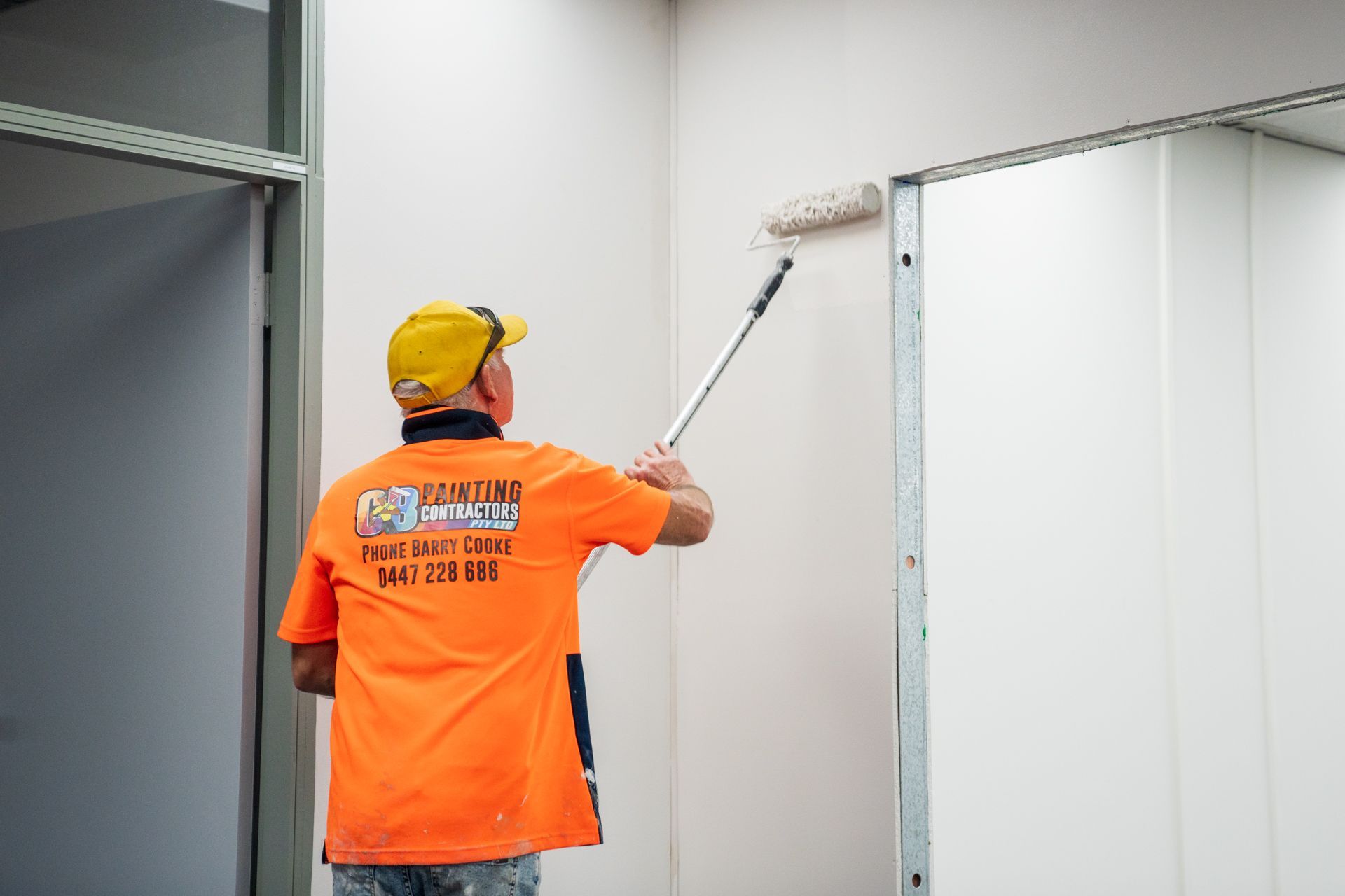 A man is painting a wall with a roller.