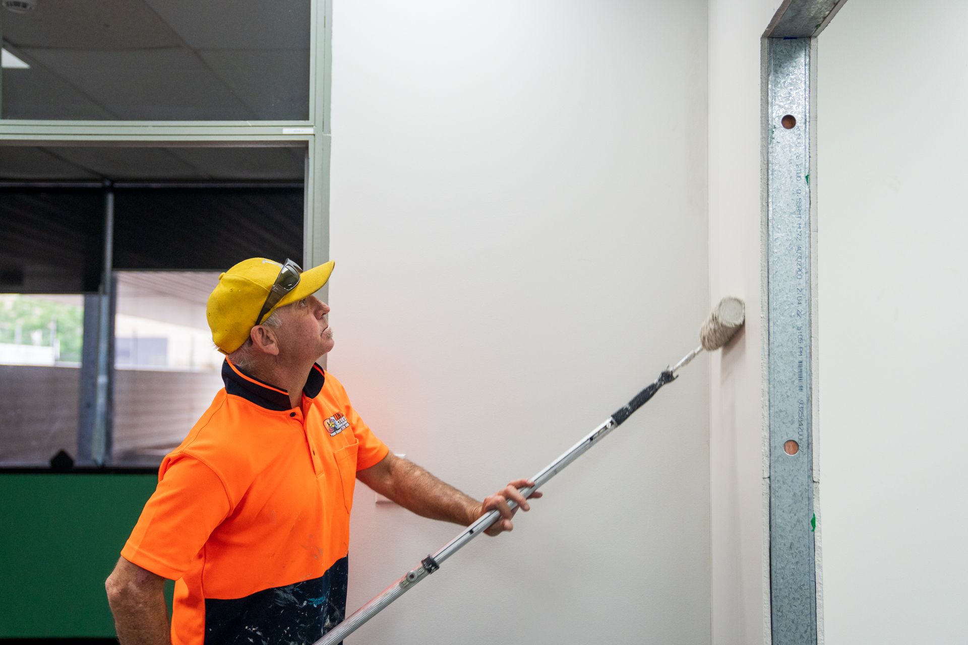 A man is painting a wall with a paint roller.
