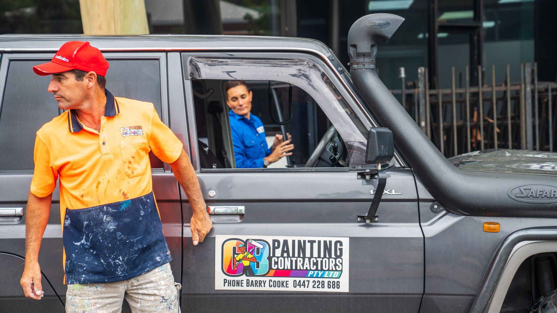 A man and a woman are standing next to a painting van.