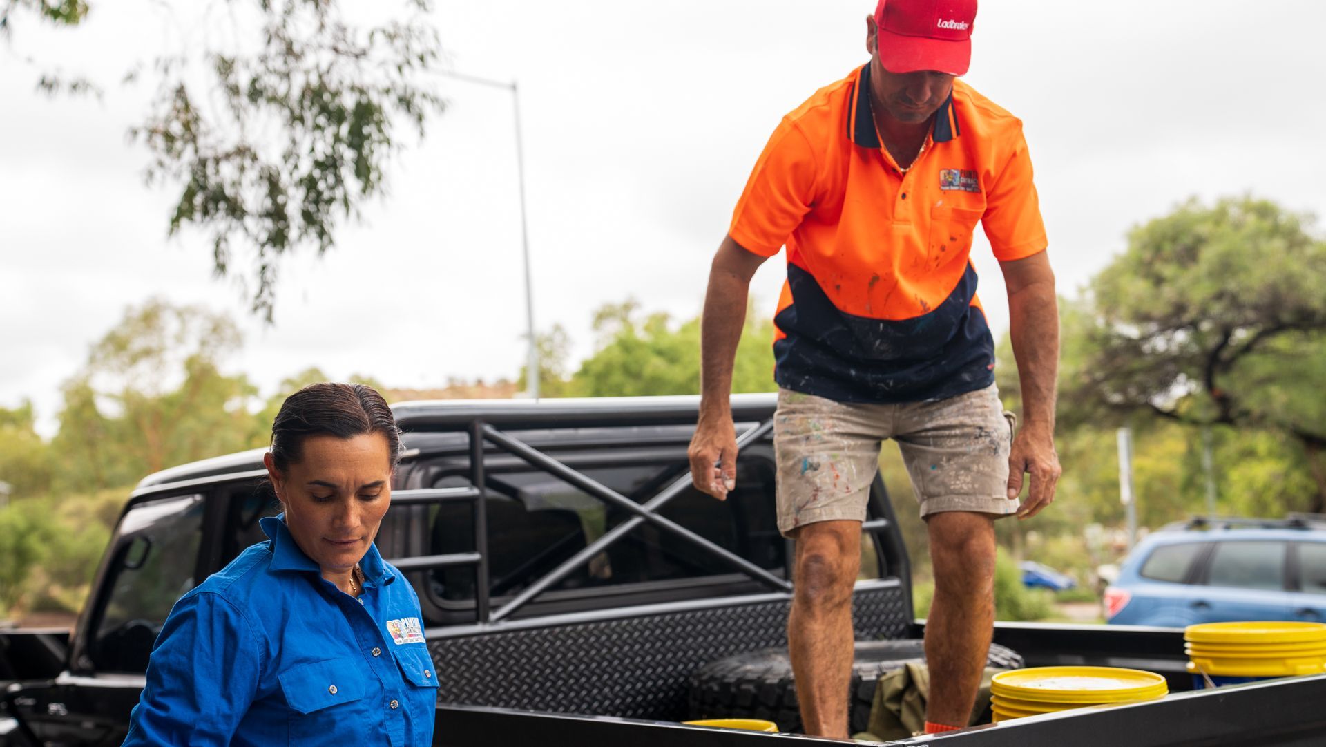 A man and a woman are standing in the back of a truck.