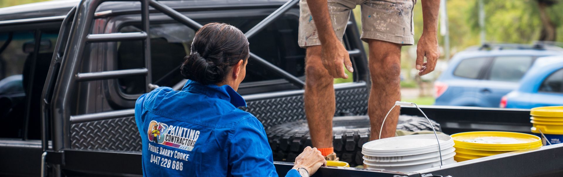 A man and a woman are standing in the back of a truck.