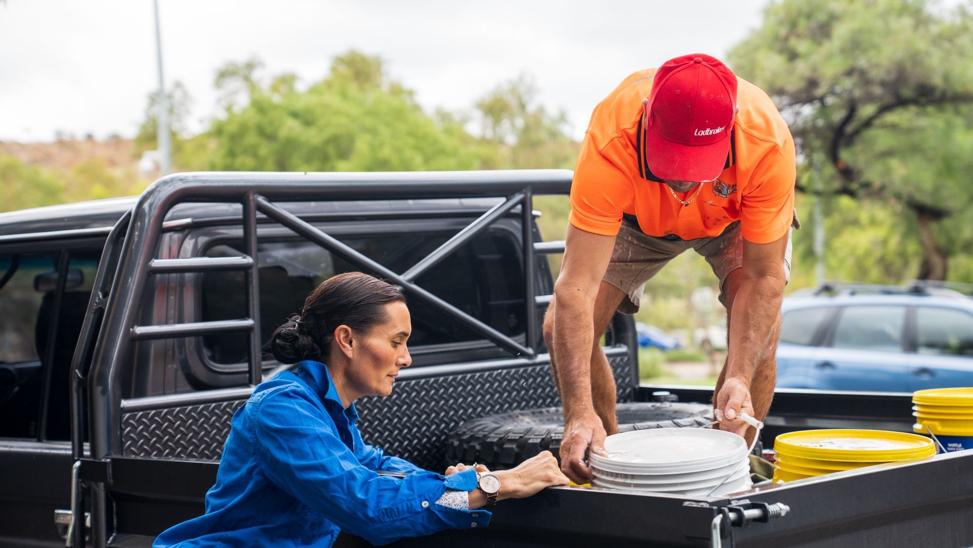A man and a woman are loading plates into the back of a truck.