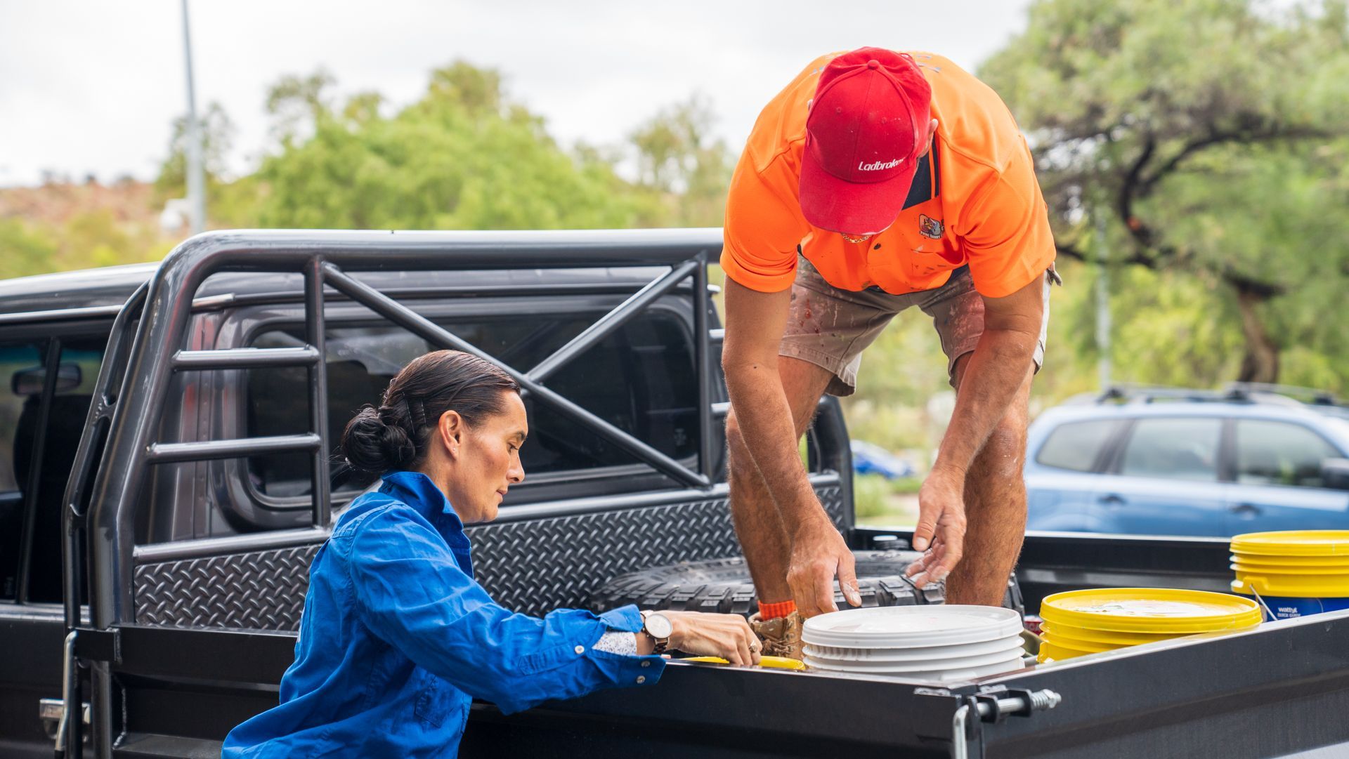 A man and a woman are loading plates into the back of a truck.