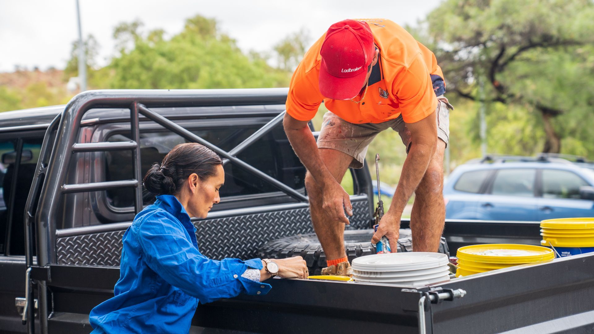 A man and a woman are working on the back of a truck.