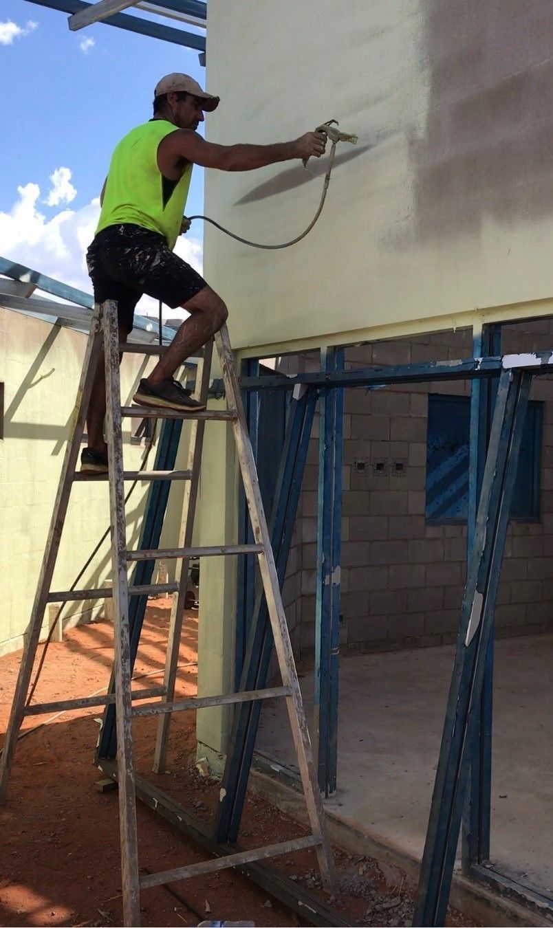 A man is standing on a ladder painting a wall.