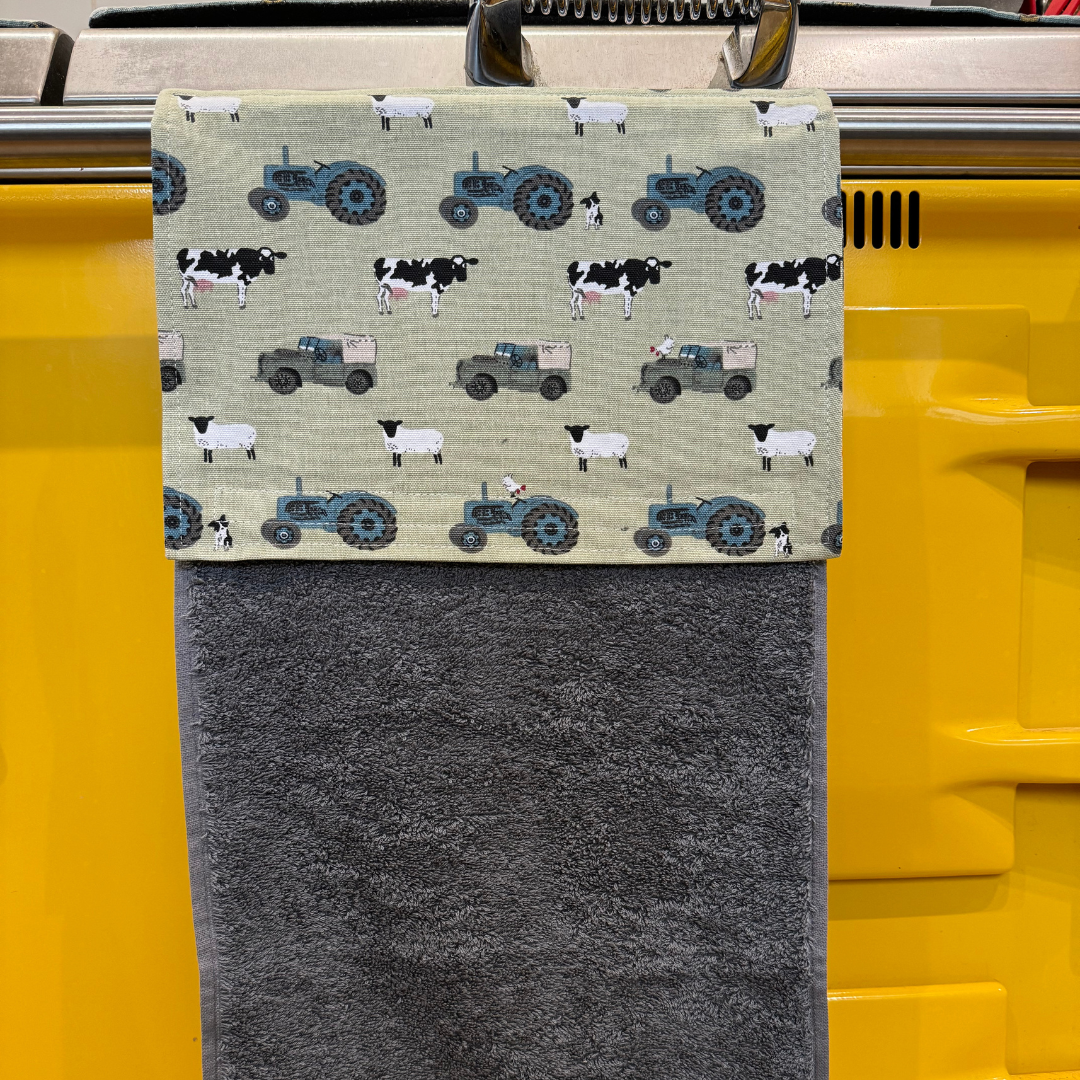 A towel with tractors and sheep on it is hanging on a yellow door.
