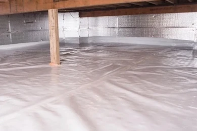 A crawl space with a clean, white vapor barrier covering the ground and silver insulation lining the foundation walls.