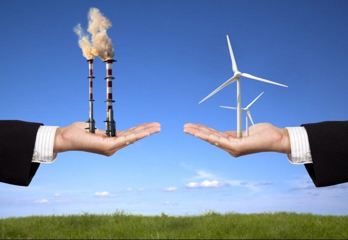 A person is holding a wind turbine and a chimney in their hands
