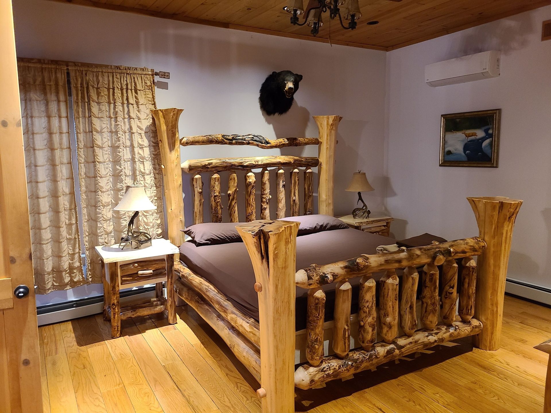 A bedroom with a wooden bed and a painting on the wall