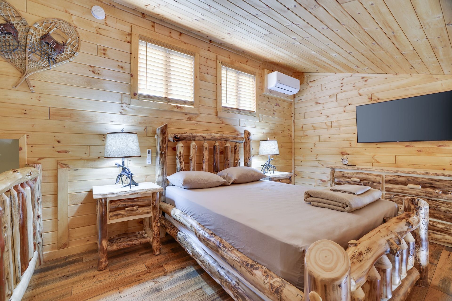 A bedroom in a log cabin with a king size bed and a flat screen tv.