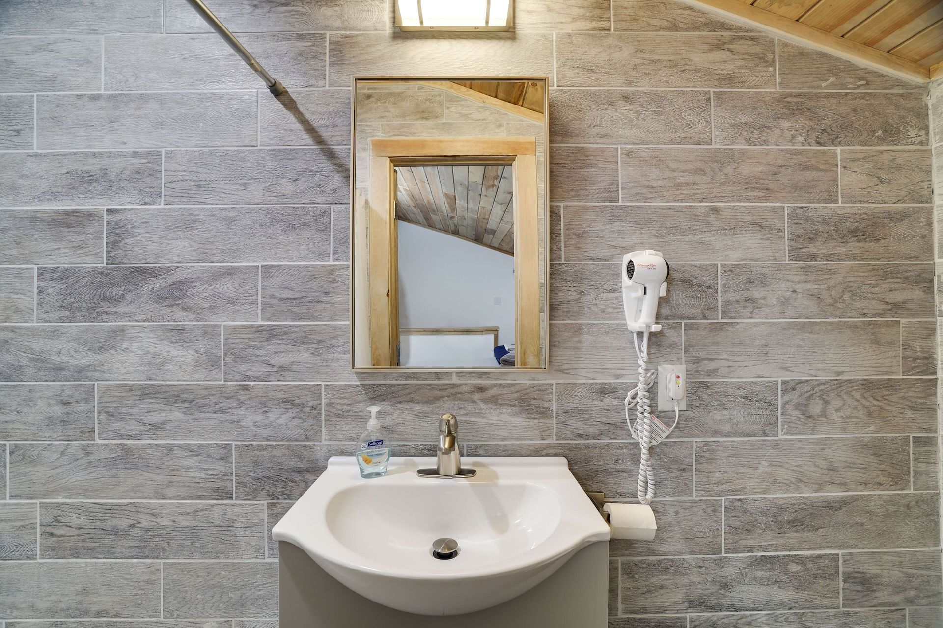 A bathroom with a sink , mirror and hair dryer.