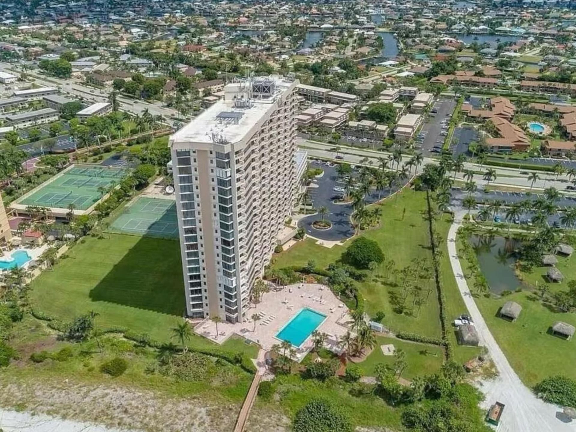 An aerial view of a large building with a pool in the middle of a city.