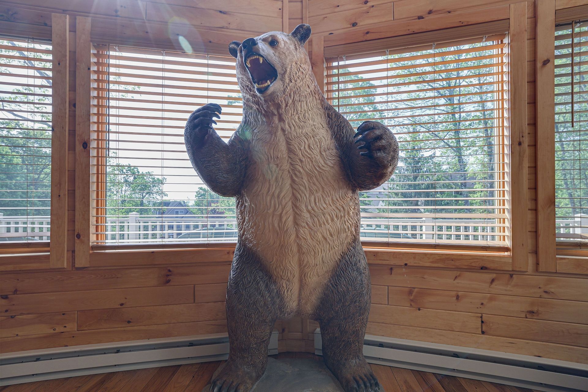 A statue of a bear is standing in front of a window in a room.