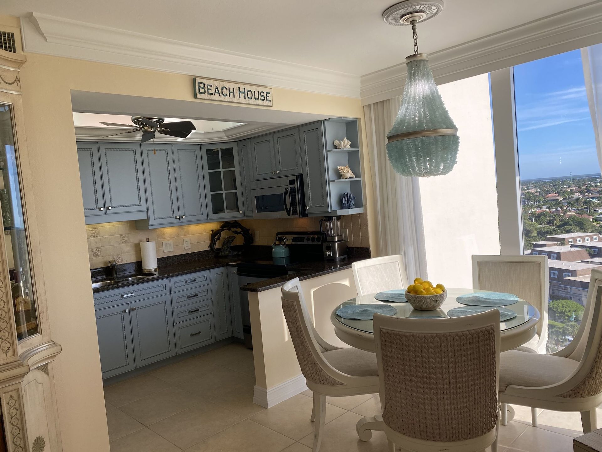 A kitchen with a table and chairs and a sign that says beach house on the wall.