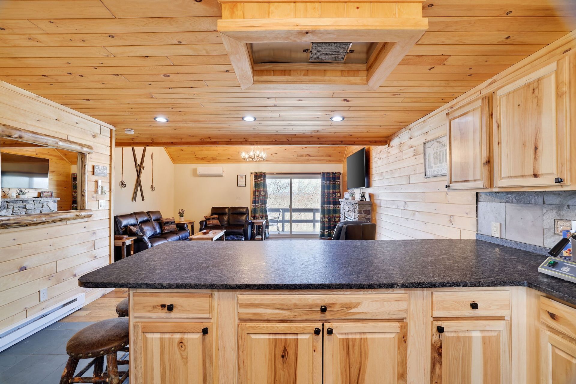 A kitchen in a log cabin with granite counter tops and wooden cabinets.