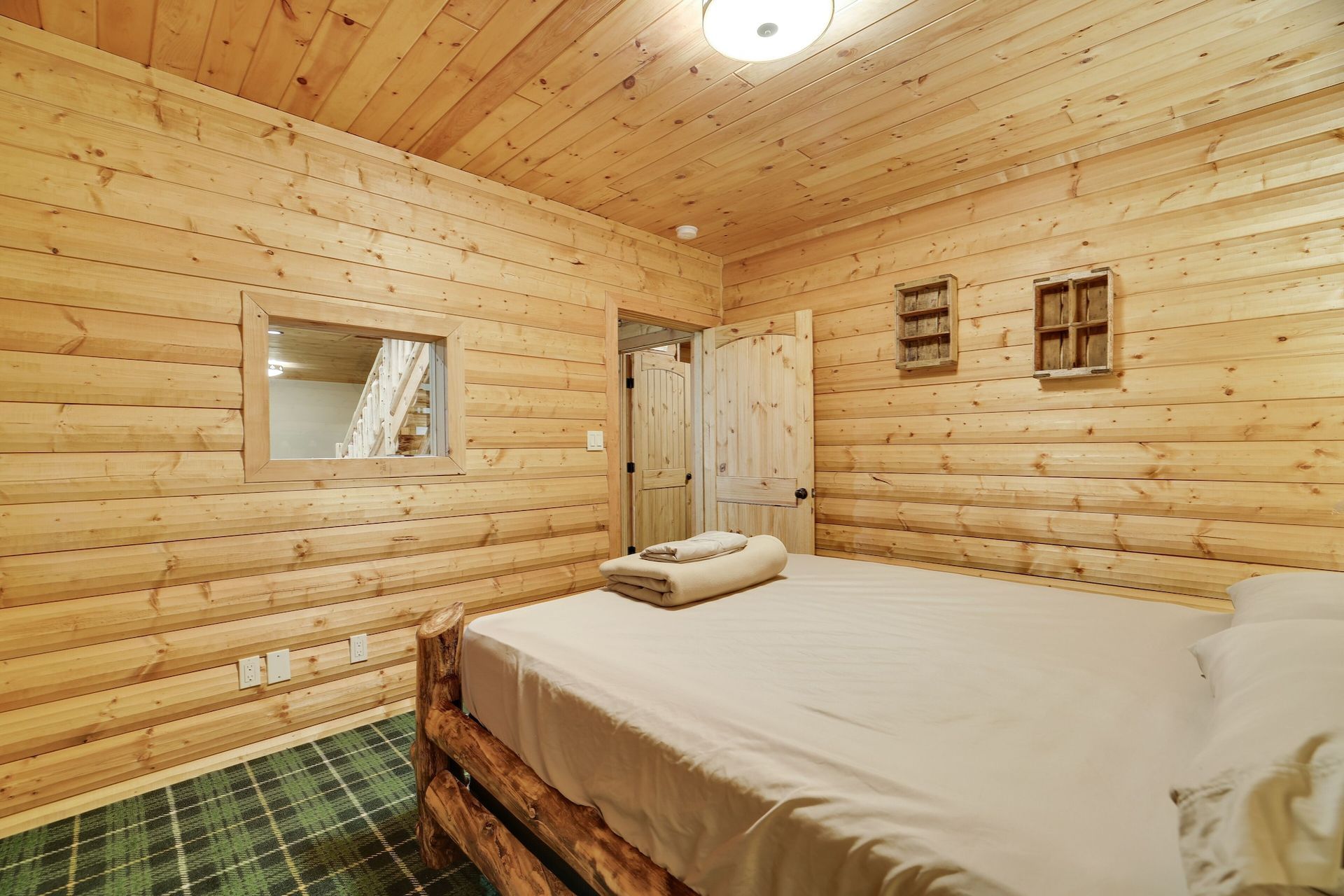 A bedroom in a log cabin with a bed and a mirror.