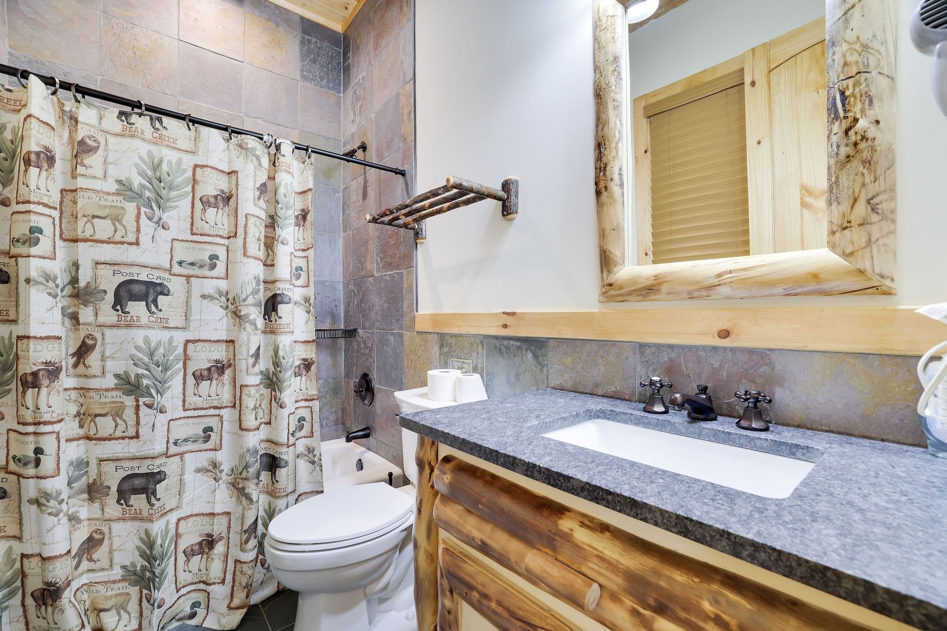 A bathroom with a toilet , sink , mirror and shower curtain.
