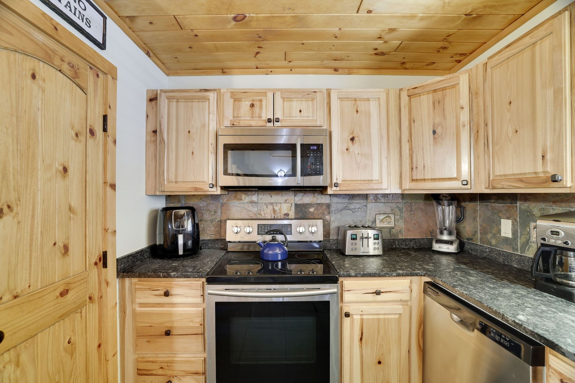 A kitchen with wooden cabinets , stainless steel appliances , and granite counter tops.