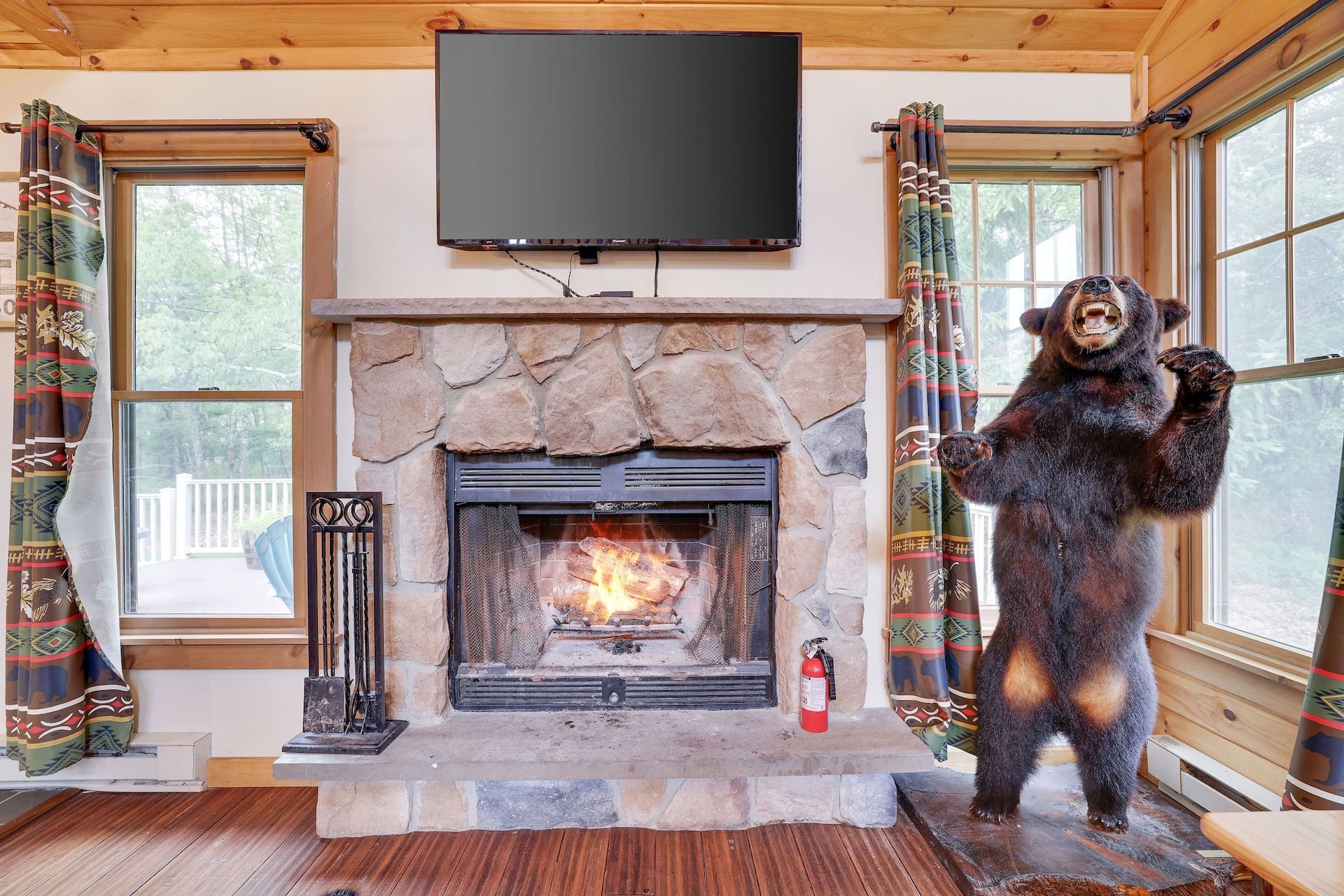 A stuffed bear is standing in front of a fireplace in a living room.